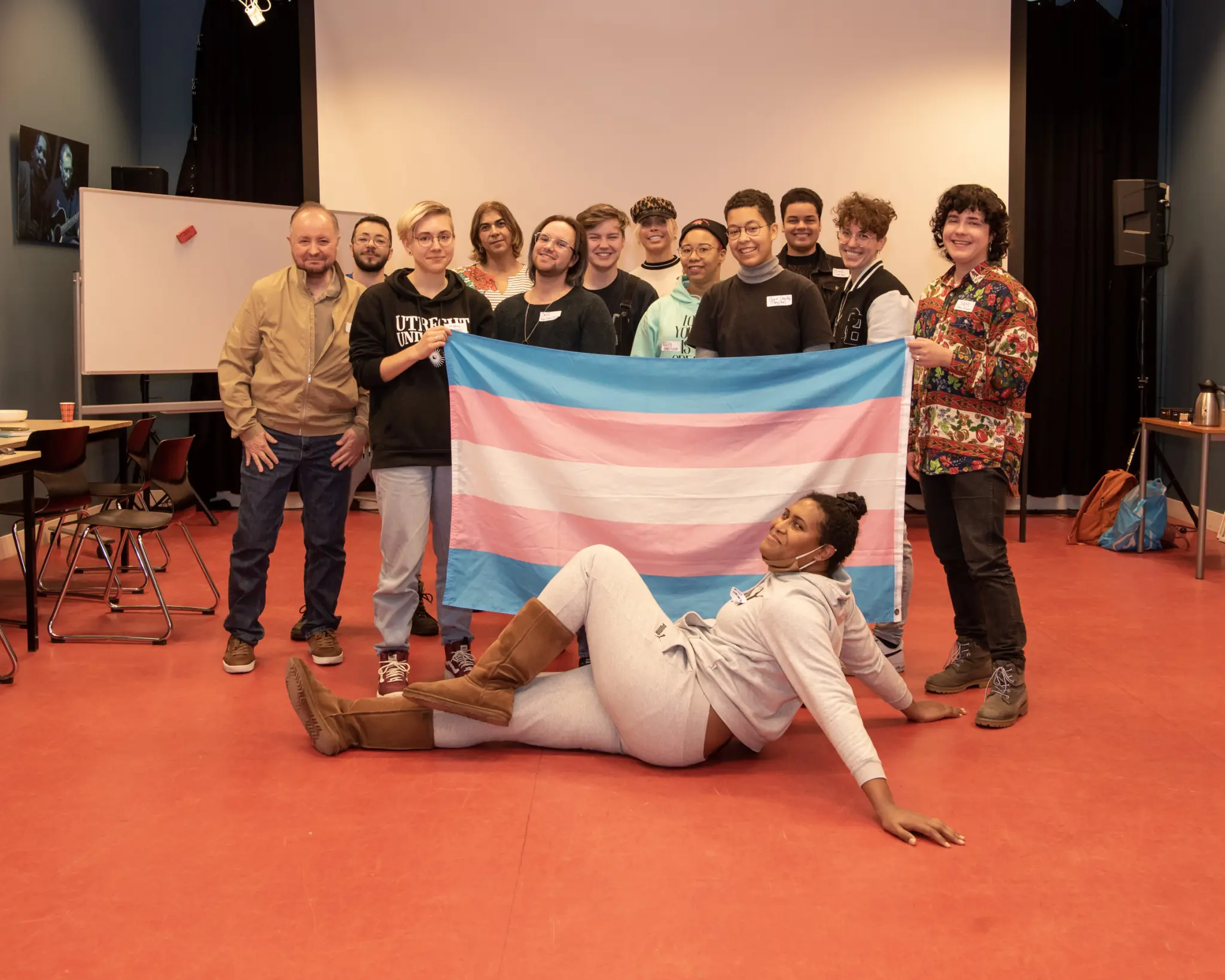 een groep queer mensen die achter een queer vlag staan